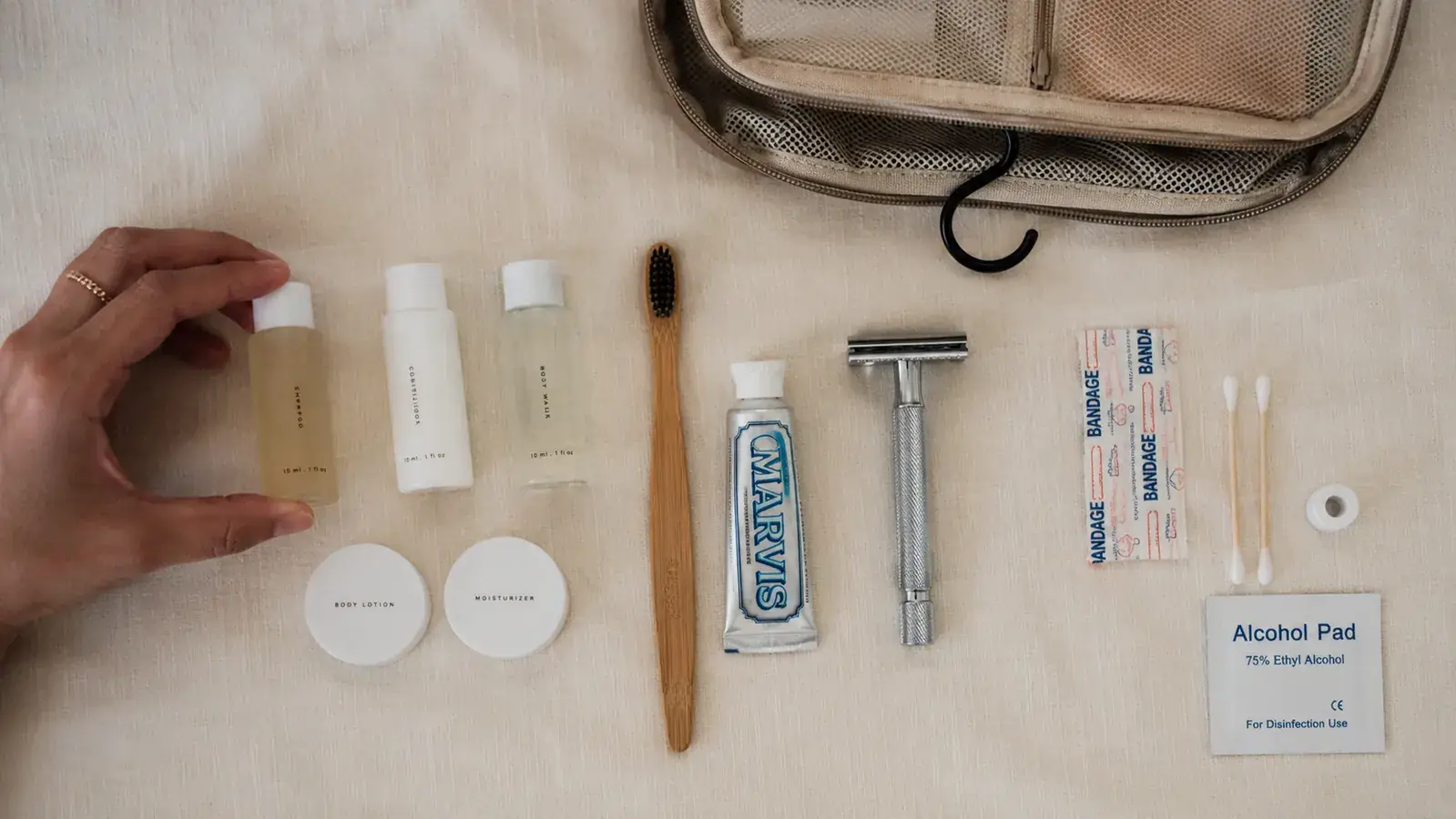Overhead flat-lay of travel toiletry essentials sorted into categories: liquids, dry items, first aid, and grooming tools