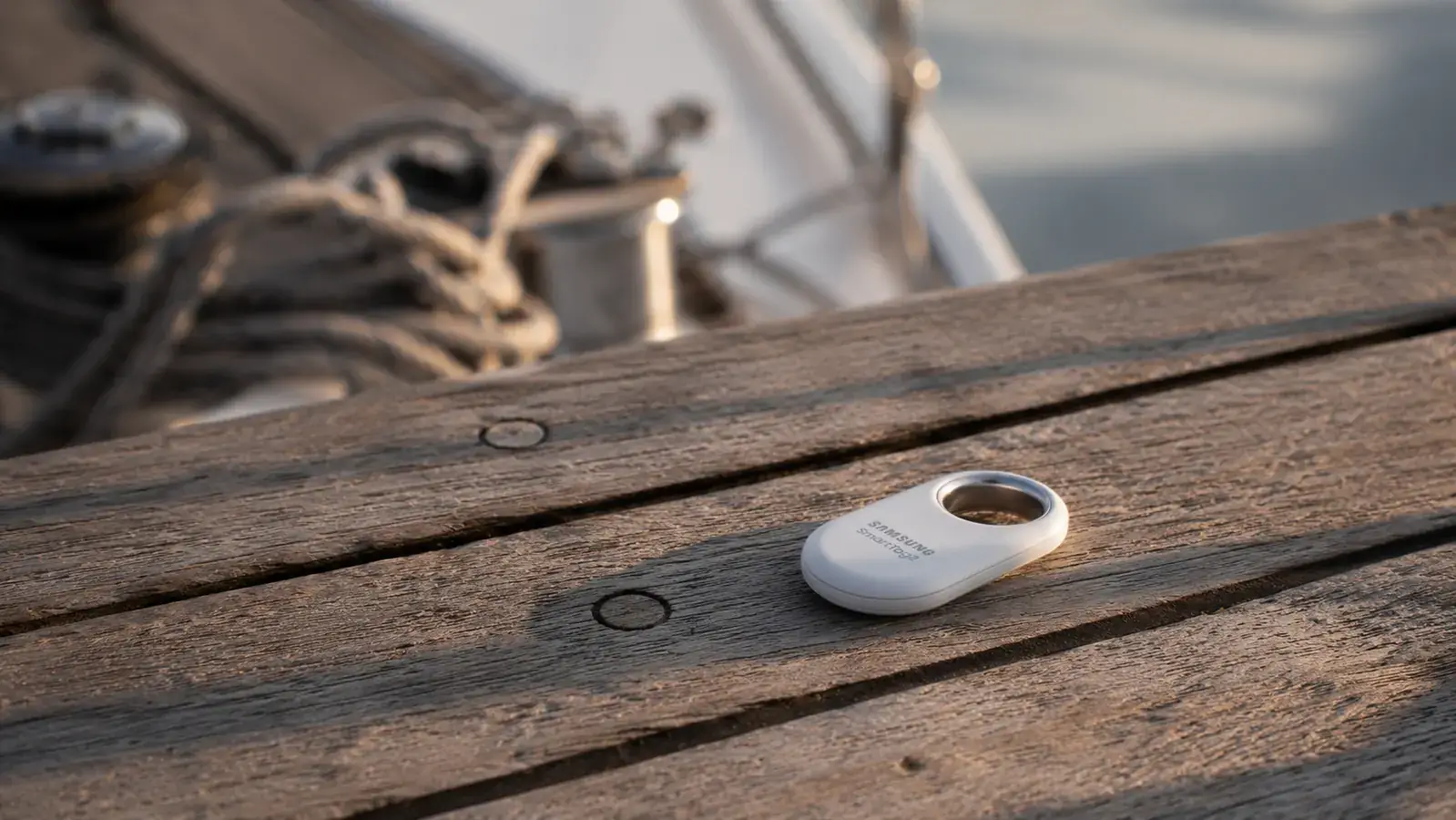 SmartTag2 sitting on a wooden dock next to a coiled rope, with sailboat rigging visible in the soft background